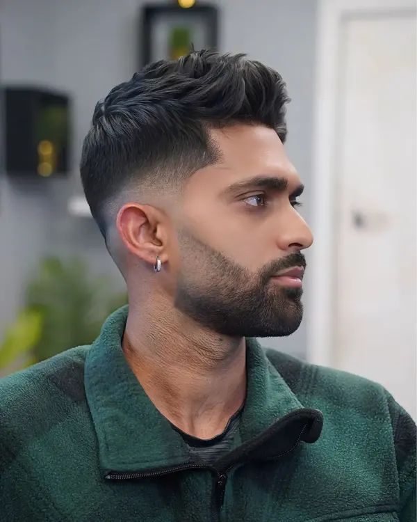 A high skin fade with a shaped full beard, in profile, cut by Leandro Herrera