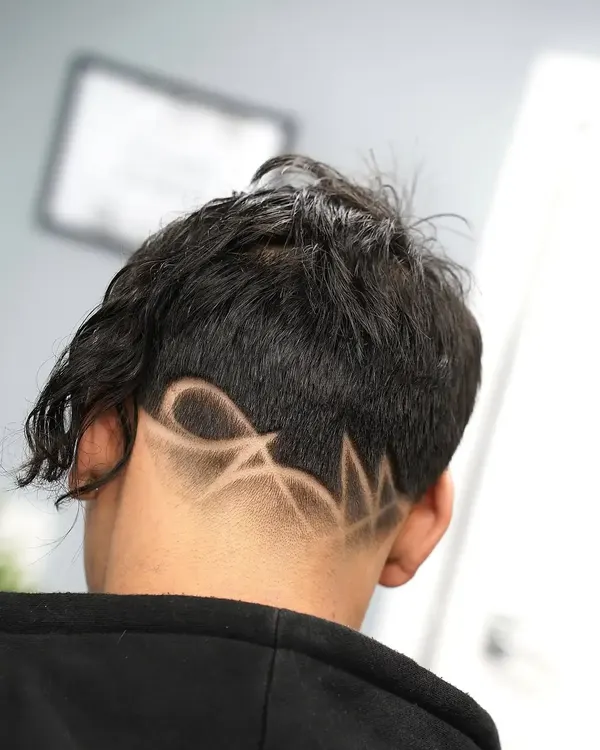 A freehand design shaved into the nape under a long textured top, cut by Leandro Herrera